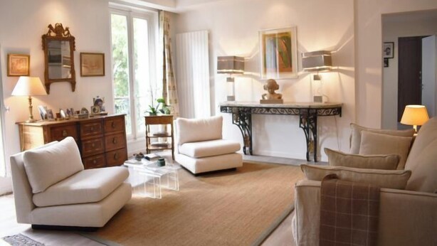 A living room with a sofa, armchairs, a coffee table, a fireplace, and a side table with lamps.