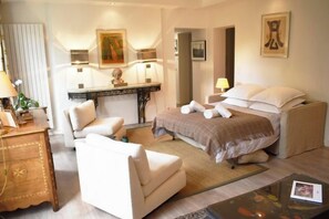Une chambre d’hôtel avec un lit, deux chaises, un bureau et une lampe.