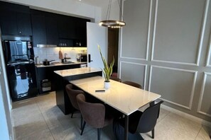 A modern kitchen with dark cabinets, a marble countertop, and a central island. - AXON Bukit Bintang Luxury Condo 3BED 2BATH (HIGH FLOOR) (Kuala Lumpur)