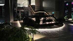 A modern indoor space with a central staircase, surrounded by potted plants and illuminated by ambient lighting. - AXON Bukit Bintang Luxury Condo 3BED 2BATH (HIGH FLOOR) (Kuala Lumpur)