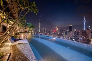 A poolside view with a city skyline in the background, including a prominent tower and a space needle. - AXON Bukit Bintang Luxury Condo 3BED 2BATH (HIGH FLOOR) (Kuala Lumpur)