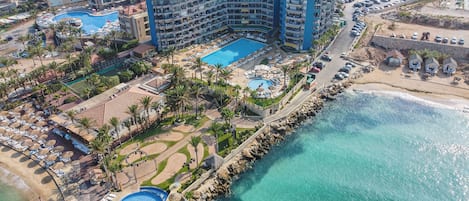 A resort with a large pool, multiple swimming areas, and a beach.