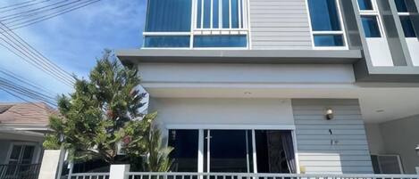 A modern two-story building with a balcony, large windows, and a gated entrance.