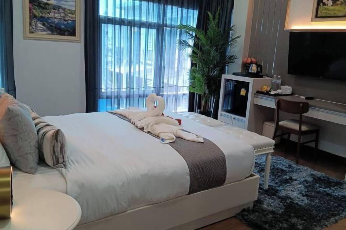 Une chambre d’hôtel avec un lit, un bureau, une télévision et une grande fenêtre avec des rideaux.