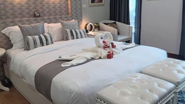 Hotellihuone, jossa on suuri sänky, yöpöytä, tuoli ja näkymä ulos.