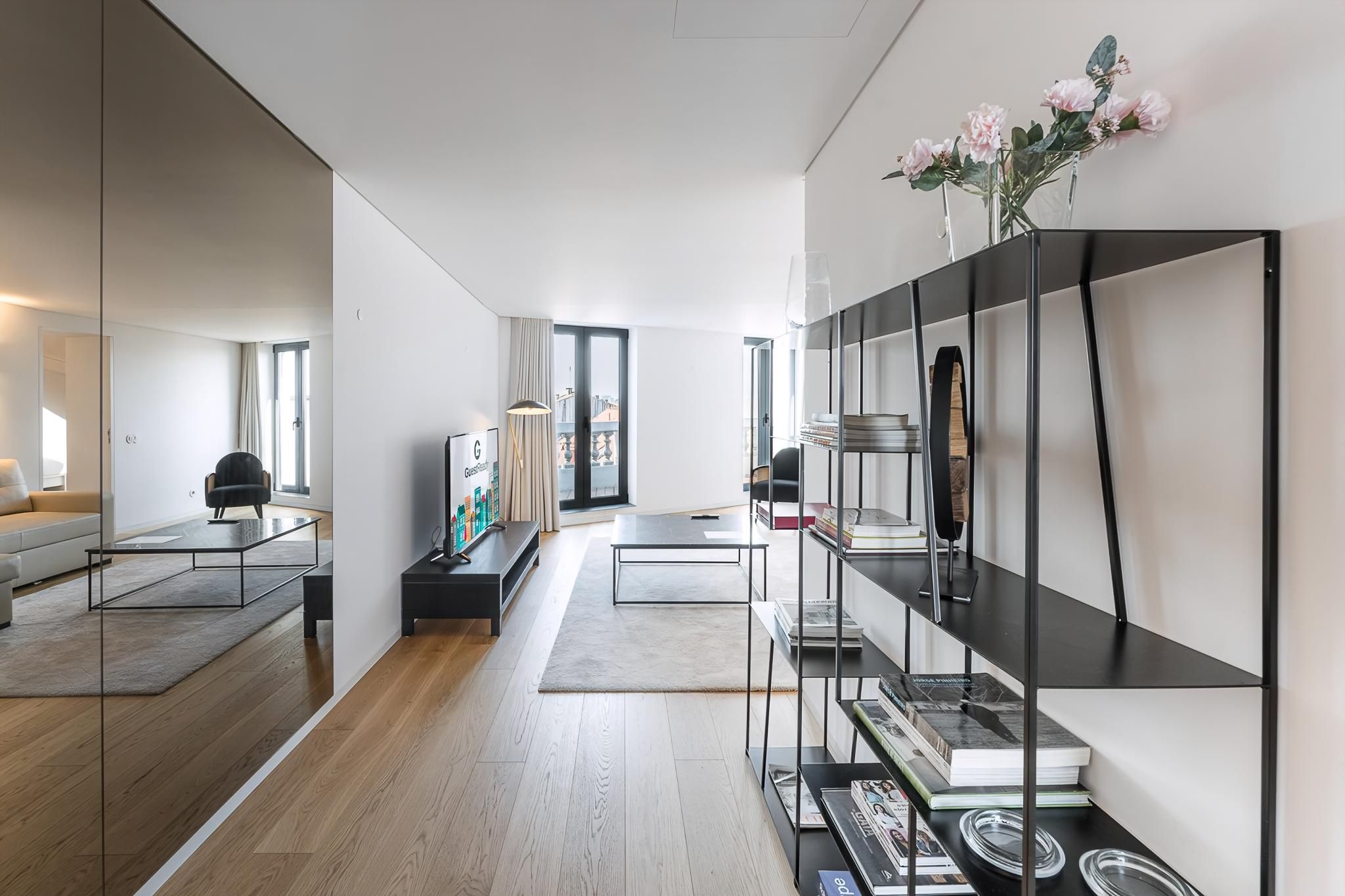 A modern living room with a sofa, coffee table, and a bookshelf with books and decorative items.