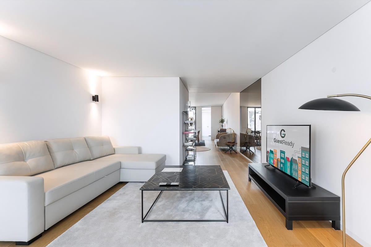 Una sala de estar moderna con un sofá, una mesa de centro, un televisor y una lámpara.