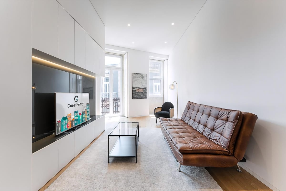 Una sala de estar moderna con un sofá, una mesa de centro, un televisor y vistas al exterior.