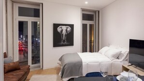 A modern bedroom with a bed, a TV, and a dining area with plates and glasses. - Guestready - Casas de Mompilher (Porto)