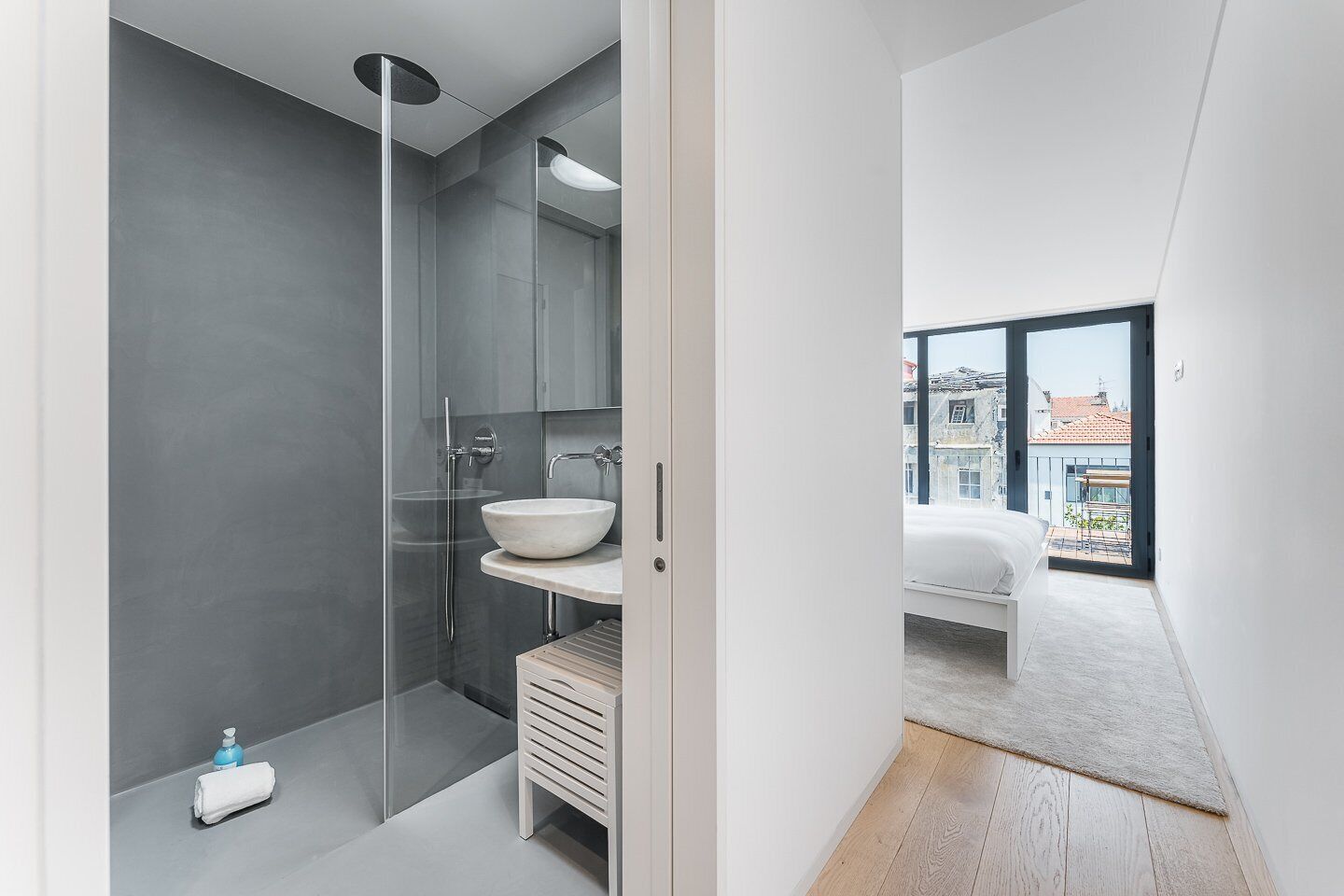 A modern bathroom with a glass shower enclosure, a white sink, and a small wooden cabinet.