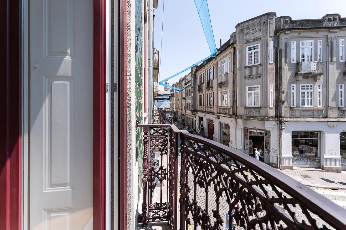 Een balkon met gedetailleerd metalen hekwerk, met uitzicht op een straat met historische gebouwen.
