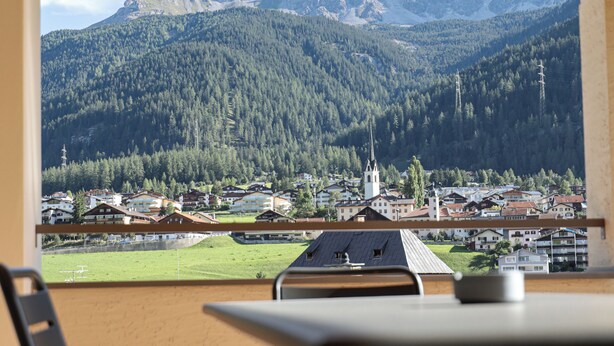Un balcon offrant une vue sur une chaîne de montagnes et sur une ville située en contrebas.