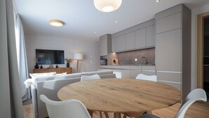 Une cuisine moderne avec des meubles gris, une table à manger en bois et des chaises blanches.