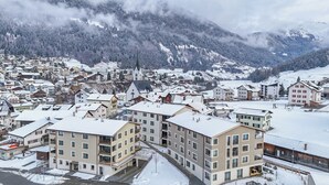 Une ville enneigée, avec des bâtiments modernes, dont un hôtel imposant à plusieurs étages et doté de nombreux balcons.