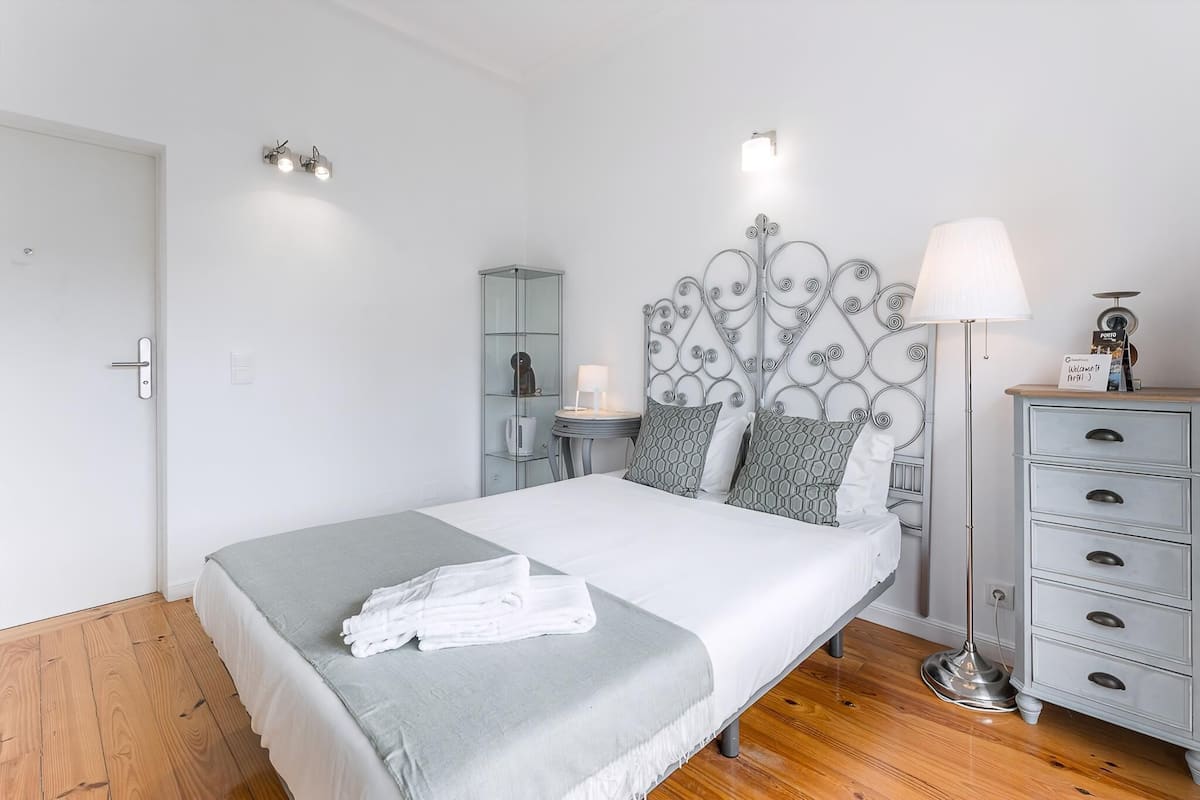 A neatly arranged bedroom with a bed, bedside table, lamp, and a dresser.