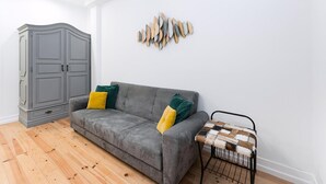 A room with a grey sofa, a patterned chair, a grey wardrobe, and a wall art piece. - Guestready - Gold Leaf (Porto)