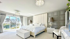 Une chambre spacieuse avec un grand lit, une coiffeuse et un lustre.