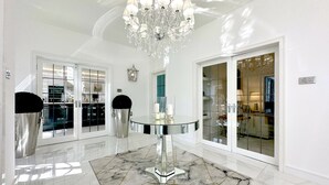 Un hall d’entrée spacieux et bien éclairé, doté d’un sol en marbre, d’une table à manger au plateau en verre et d’un lustre en cristal.