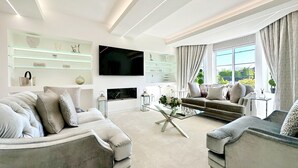 Un salon moderne comprenant un canapé, une table basse et un téléviseur à écran plat fixé au mur.