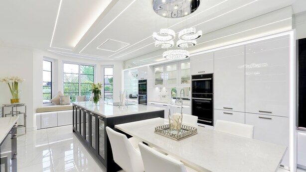 Une cuisine moderne avec des meubles blancs, un îlot central et des luminaires suspendus.