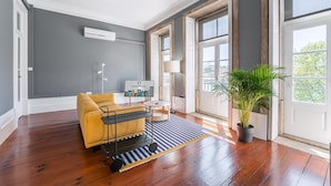 A modern living room with a sofa, a small table, a lamp, and a potted plant. - Guestready - Innvict Residences (Porto)