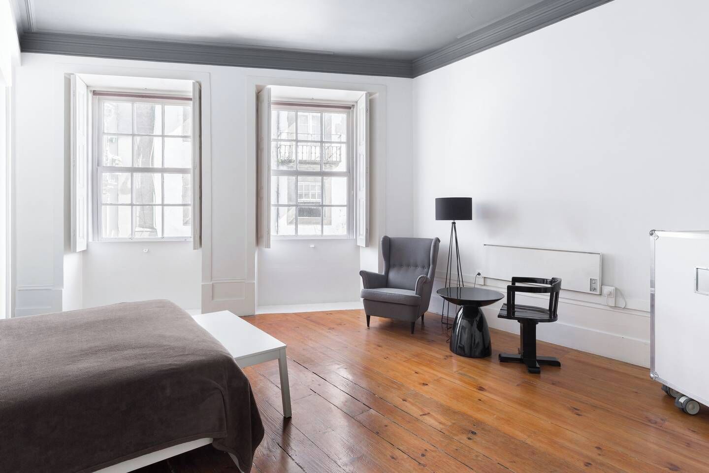 Una habitación con una cama, una silla, una mesita y una lámpara de pie.