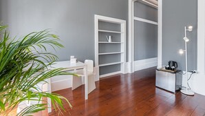 A room with a wooden floor, white furniture, a plant, and a built-in shelving unit. - Guestready - Innvict Residences (Porto)