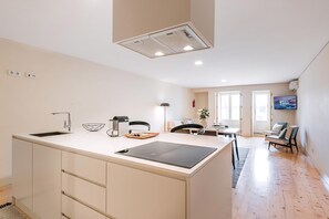 Una cocina moderna con una isla integrada, un área de comedor con una mesa y sillas, y un televisor montado en la pared.