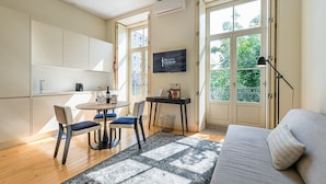 Un salon moderne comprenant un canapé, une table à manger avec des chaises, un téléviseur et une grande fenêtre donnant sur un paysage verdoyant.