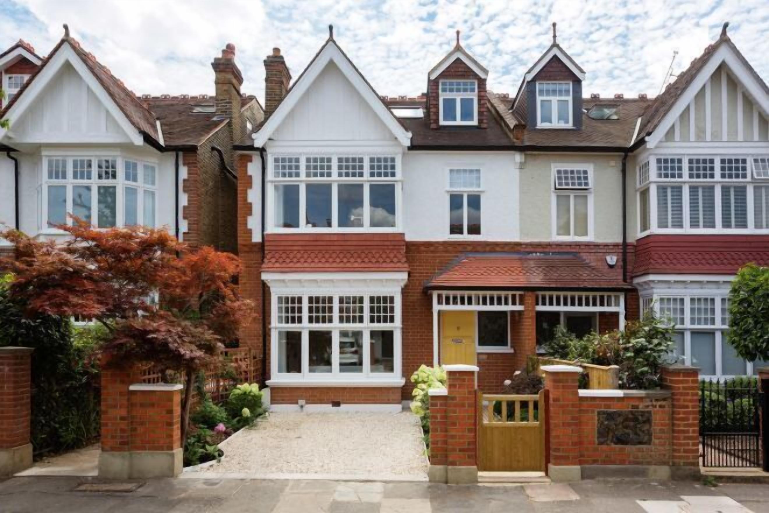 A row of two-story houses with pitched roofs, brick exteriors, and white-framed windows.