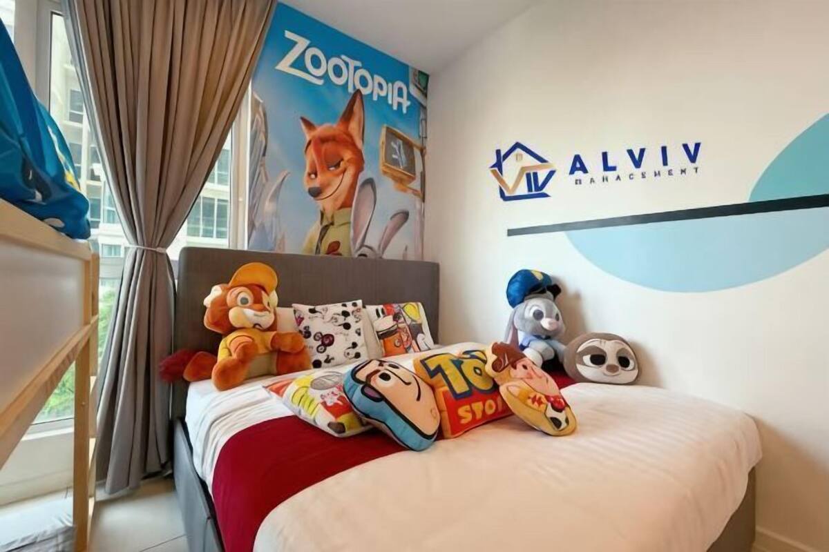 Quarto de hotel com uma cama, um cartaz de personagem de desenho animado e um logotipo na parede.