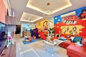 A modern living room with a LEGO-themed wall, a sofa, a coffee table, and a play area with toys.
