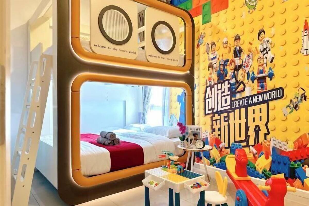 Ein Zimmer mit einem Etagenbett, einem kleinen Tisch mit Spielzeug sowie einer Wand, die mit LEGO-Figuren und Text verziert ist.