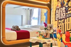 A hotel room with a bed, a small table with toys, and a wall with colorful decorations.