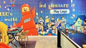 Leikkialue, jossa on suuri LEGO-hahmo ja useita pienempiä LEGO-minihahmoja.