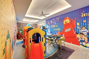 Ein Kinderspielbereich mit einer LEGO-Wand, einer Spielkonstruktion und einem Esstisch.