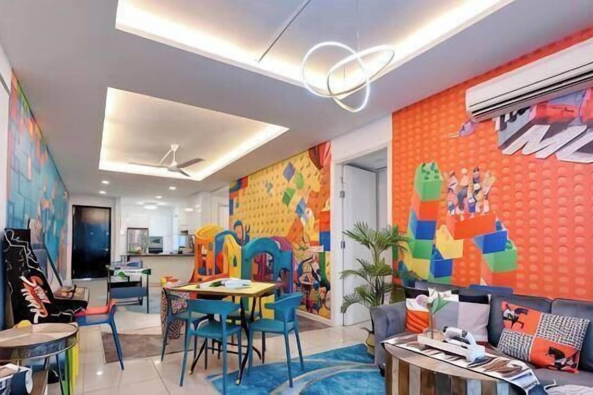 Um interior moderno com área de jantar, obras de arte coloridas e uma TV de tela plana.