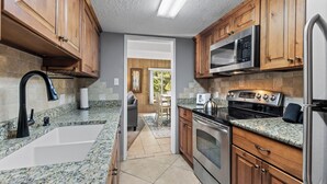 A kitchen with granite countertops, wooden cabinets, stainless steel appliances, and a view to a dining area. - Top-Floor 2BR Condo Steps from Lifts. Pool/Hot Tub (Breckenridge)