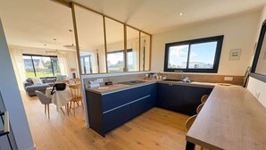 Eine moderne Küche mit einer großen Kochinsel, Holzböden und einem Essbereich mit Tisch und Stühlen.