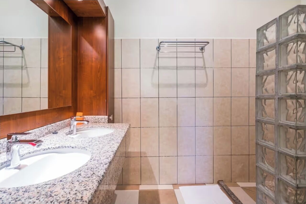 A bathroom with two sinks, a mirror, and a shower area.
