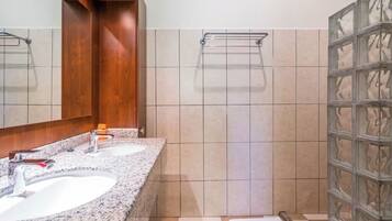 A bathroom with two sinks, a mirror, and a shower area.