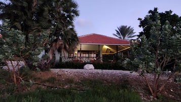 A building with a red roof, surrounded by palm trees and other vegetation.