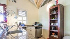 A kitchen with granite countertops, a dishwasher, a wooden cabinet, and a window with blinds. - Enjoy a spacious modern Villa, situated next to Golf Course and Pool and Beach (Sint Michiel)