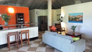 A spacious living area with a kitchen, a dining table, and a sofa. - Enjoy a spacious modern Villa, situated next to Golf Course and Pool and Beach (Sint Michiel)