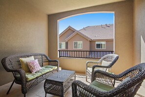 A balcony with wicker furniture and a view of a house. - Pebble Beach Retreat (Washington)