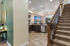 A kitchen with a central island, dark wooden cabinets, and a large painting above the island. - Pebble Beach Retreat (Washington)