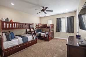 A bedroom with two bunk beds, a ceiling fan, a desk with a clock, and a window with blinds. - Pebble Beach Retreat (Washington)