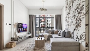 A modern living room with a grey sofa, a round coffee table, and a TV mounted on the wall.