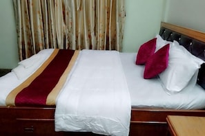 A bed with a wooden headboard, white bedding, and a red and gold striped blanket. - Ojas Home Bharatpur (Bharatpur)