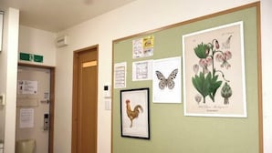A bulletin board with various notices, a framed rooster illustration, and botanical prints.